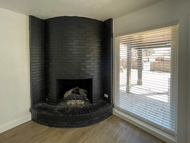 room details featuring a fireplace, baseboards, and wood finished floors