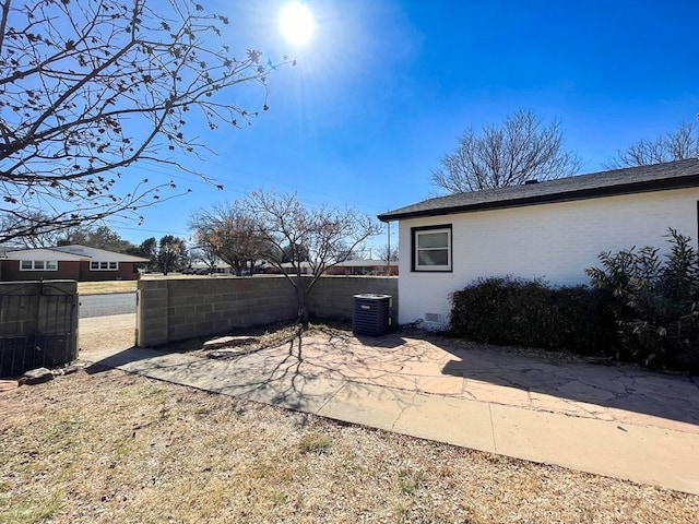 view of yard with central AC unit, fence, and a patio