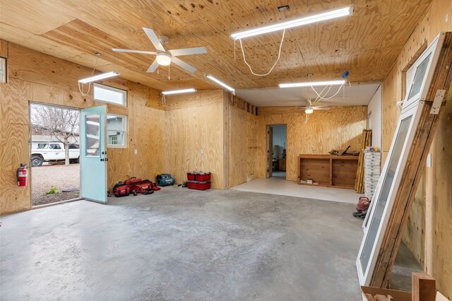 garage featuring ceiling fan, wood ceiling, and wood walls