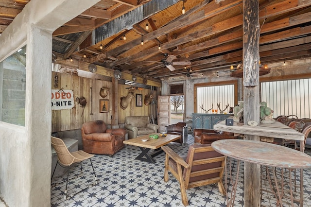 interior space with beamed ceiling, ceiling fan, and wooden walls