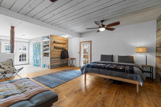 bedroom featuring ceiling fan, light hardwood / wood-style flooring, wooden ceiling, and wood walls