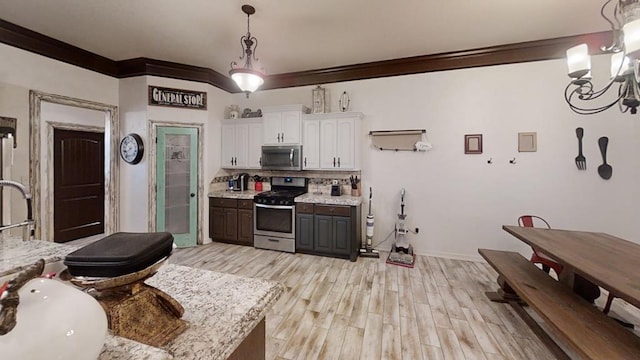 kitchen with light wood-type flooring, stainless steel appliances, crown molding, a notable chandelier, and white cabinetry