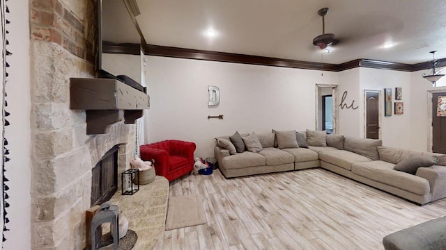 living room featuring light hardwood / wood-style flooring, ornamental molding, and a stone fireplace