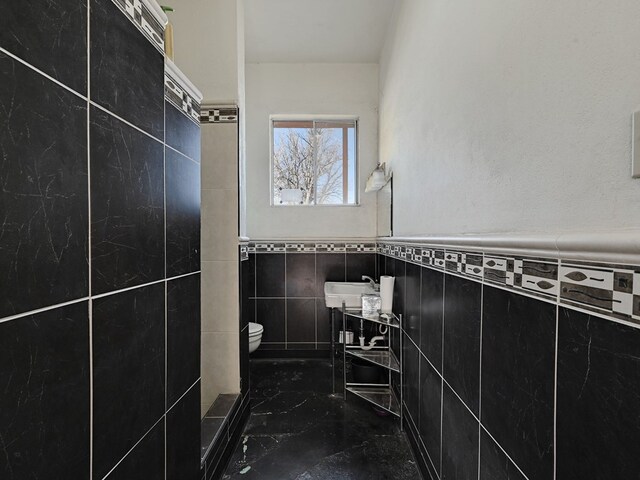 bathroom with tile walls and toilet