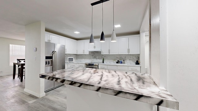 kitchen with backsplash, pendant lighting, appliances with stainless steel finishes, and white cabinets