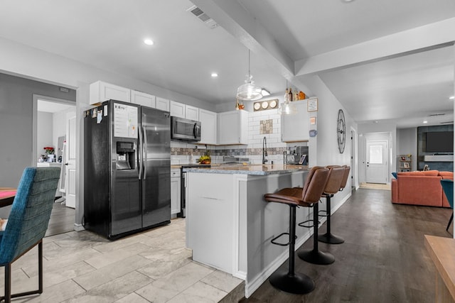 kitchen with appliances with stainless steel finishes, pendant lighting, white cabinetry, decorative backsplash, and light stone counters