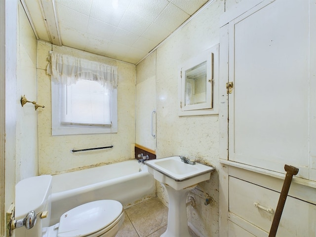 bathroom featuring tile patterned flooring, a tub, and toilet