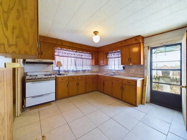 kitchen with sink, white gas stove, and backsplash