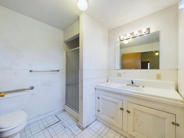 bathroom with toilet, vanity, and a shower with shower door