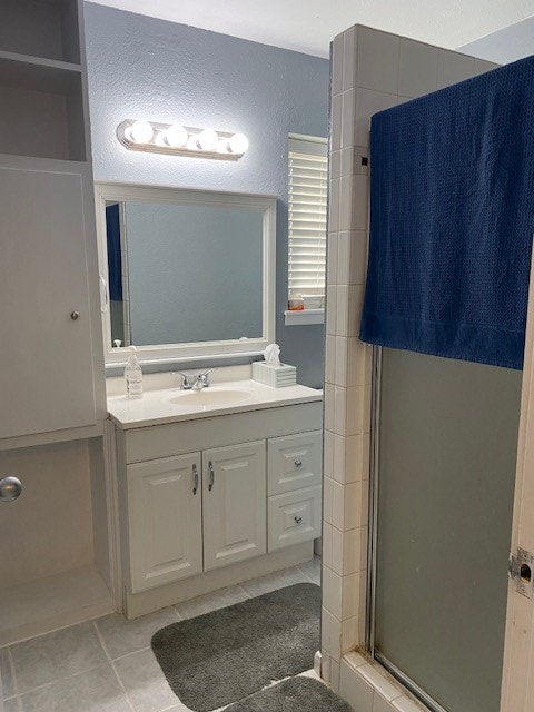 bathroom with walk in shower, vanity, and tile patterned flooring