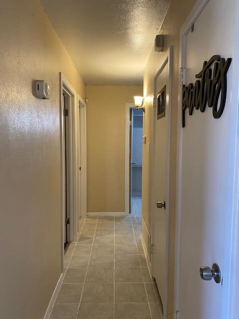 hall with tile patterned floors