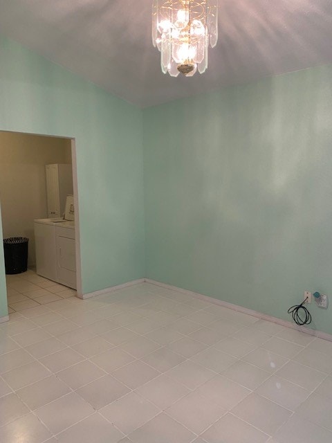 tiled empty room with an inviting chandelier and independent washer and dryer