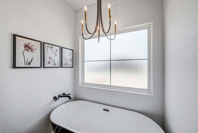 bathroom with a tub to relax in and a chandelier