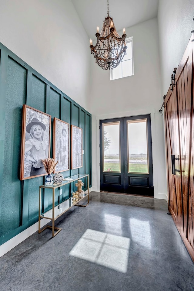 foyer featuring a chandelier, a barn door, a high ceiling, and french doors