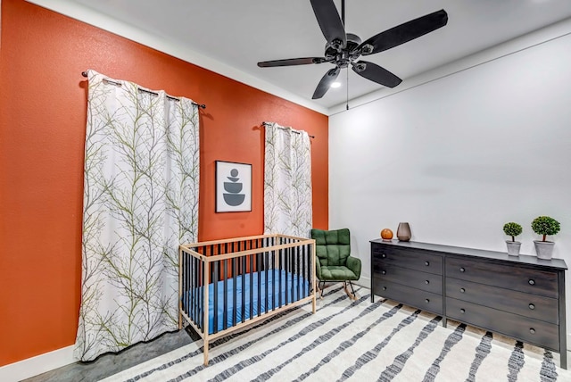 bedroom with ceiling fan and a crib