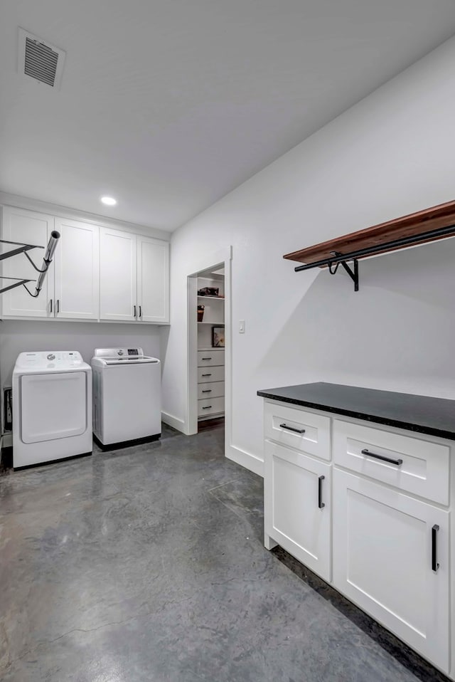 clothes washing area featuring cabinets and washer and dryer