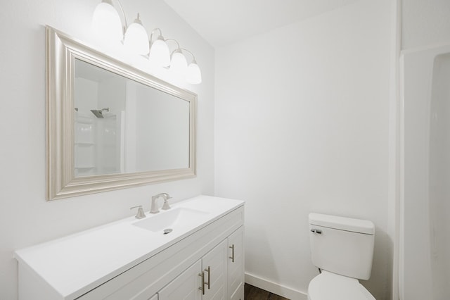 bathroom with toilet, baseboards, and vanity