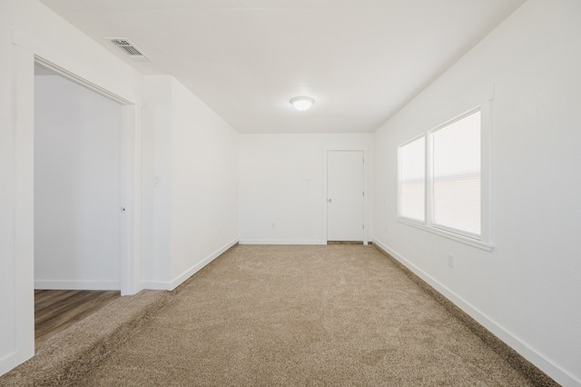 empty room featuring visible vents, light carpet, and baseboards