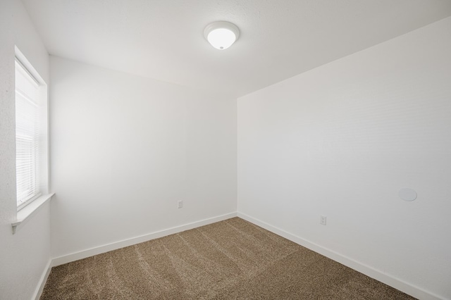 carpeted spare room featuring baseboards