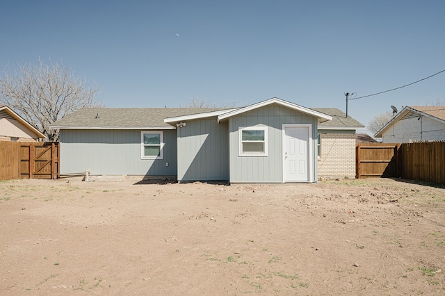 back of property featuring fence and a gate