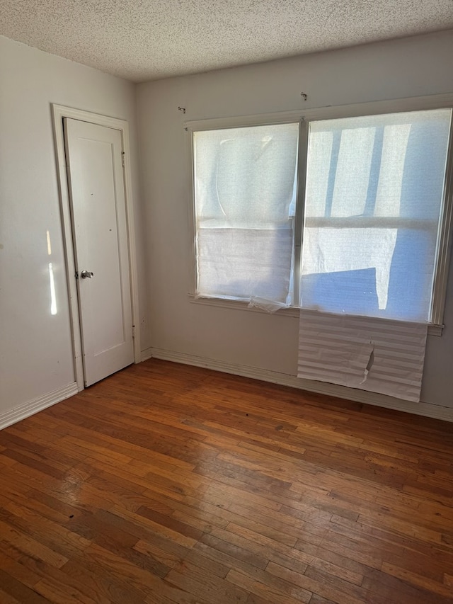 unfurnished room featuring dark hardwood / wood-style flooring, a healthy amount of sunlight, and a textured ceiling