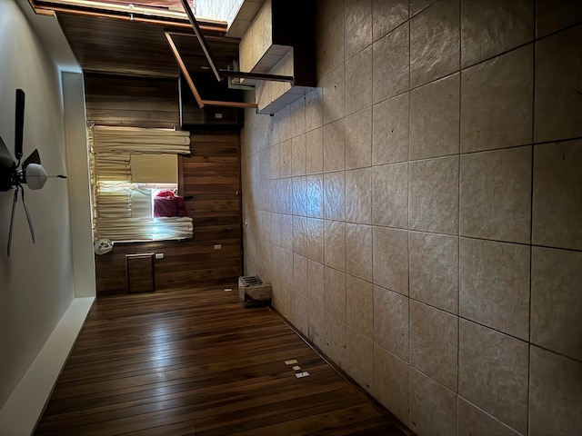 corridor featuring dark hardwood / wood-style floors and wood walls