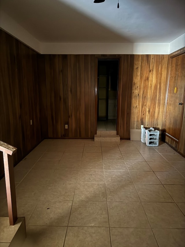 tiled empty room with wood walls and ceiling fan