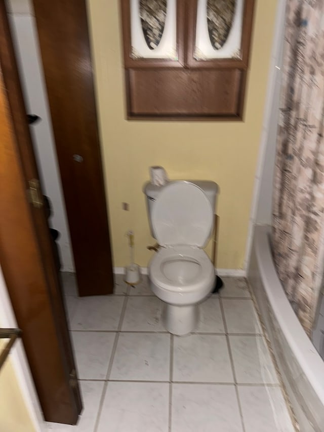 bathroom with tile patterned flooring, shower / tub combo, and toilet