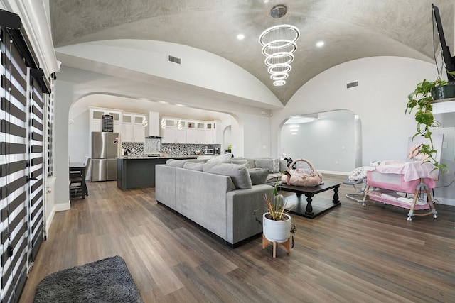 living room with an inviting chandelier, vaulted ceiling, and dark wood-type flooring