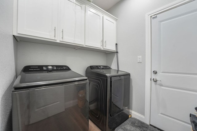 clothes washing area featuring washing machine and dryer, cabinets, and hardwood / wood-style flooring