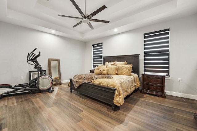 bedroom featuring a raised ceiling, ceiling fan, and hardwood / wood-style floors