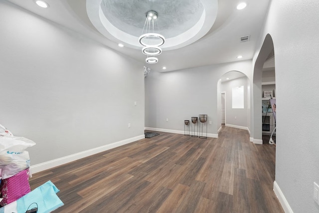 unfurnished living room featuring dark hardwood / wood-style floors and a raised ceiling