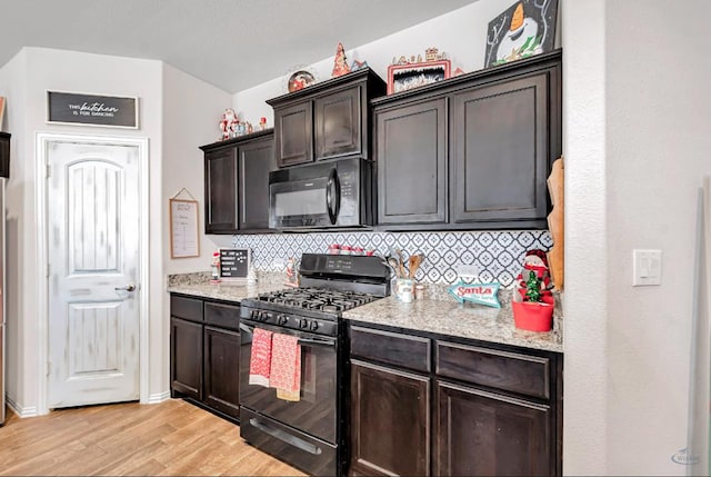 kitchen with backsplash, light stone counters, dark brown cabinets, black appliances, and light hardwood / wood-style floors