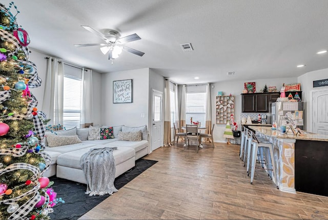 living room featuring dark hardwood / wood-style floors, ceiling fan, and a textured ceiling