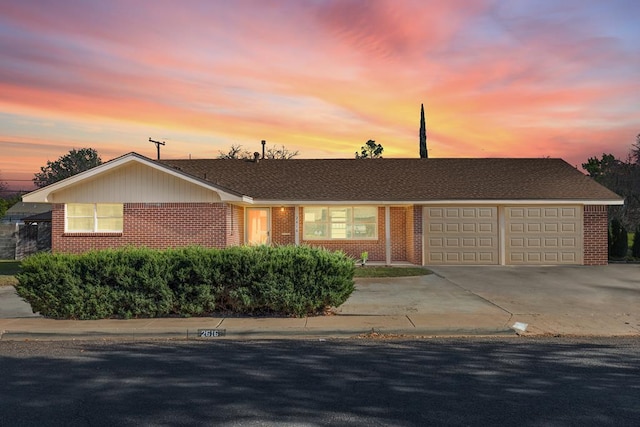 ranch-style house featuring an attached garage, concrete driveway, and brick siding