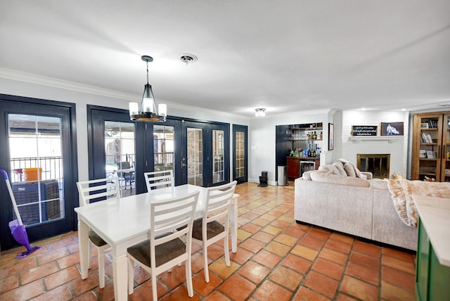 dining room with a fireplace, an inviting chandelier, french doors, and ornamental molding