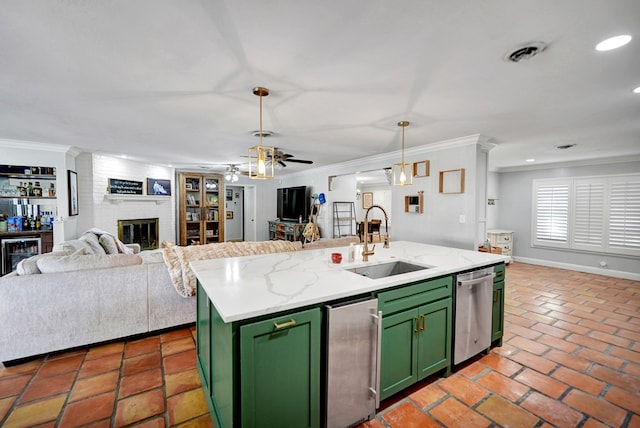 kitchen featuring a fireplace, decorative light fixtures, green cabinets, and sink