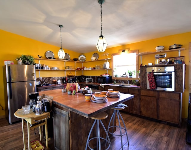 kitchen featuring dark hardwood / wood-style flooring, a center island, stainless steel appliances, and dark brown cabinets