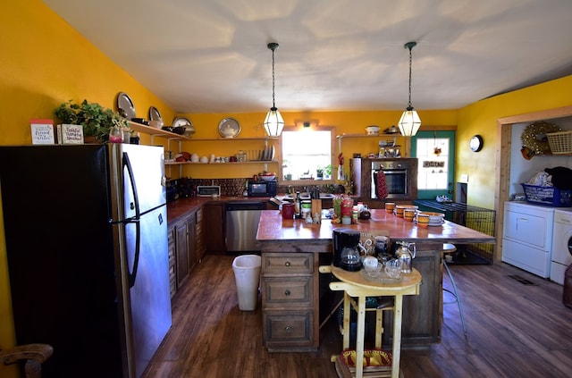 kitchen with appliances with stainless steel finishes, dark hardwood / wood-style flooring, a kitchen breakfast bar, washer and clothes dryer, and decorative light fixtures