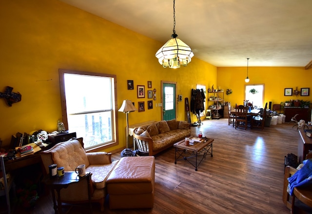 living room with dark hardwood / wood-style floors, a chandelier, and vaulted ceiling