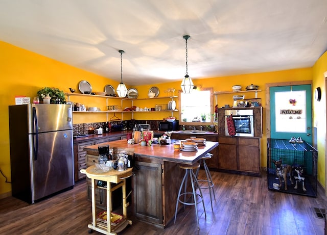 kitchen with a breakfast bar area, a kitchen island, dark wood-type flooring, and appliances with stainless steel finishes