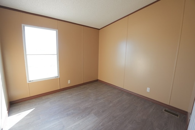 empty room with crown molding, a textured ceiling, and light hardwood / wood-style flooring