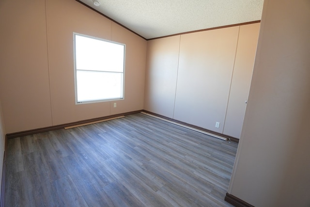 spare room with hardwood / wood-style floors, crown molding, vaulted ceiling, and a textured ceiling