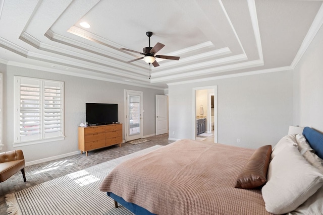 bedroom with a tray ceiling, multiple windows, baseboards, and connected bathroom