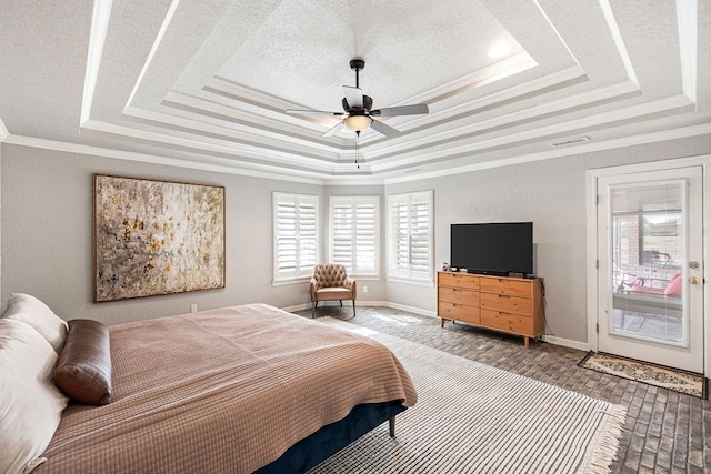 bedroom with a raised ceiling, visible vents, and ornamental molding