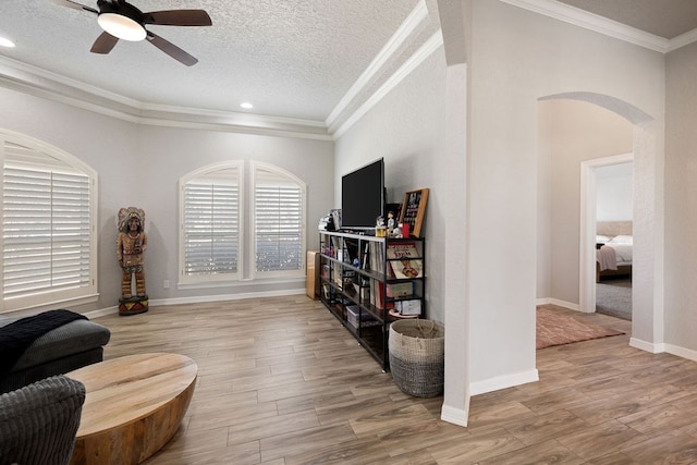 sitting room featuring wood finished floors, arched walkways, ceiling fan, and crown molding