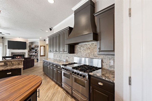 kitchen with crown molding, range with two ovens, light wood-style flooring, custom exhaust hood, and a ceiling fan