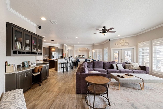 living room featuring visible vents, a textured ceiling, light wood-style floors, and a ceiling fan