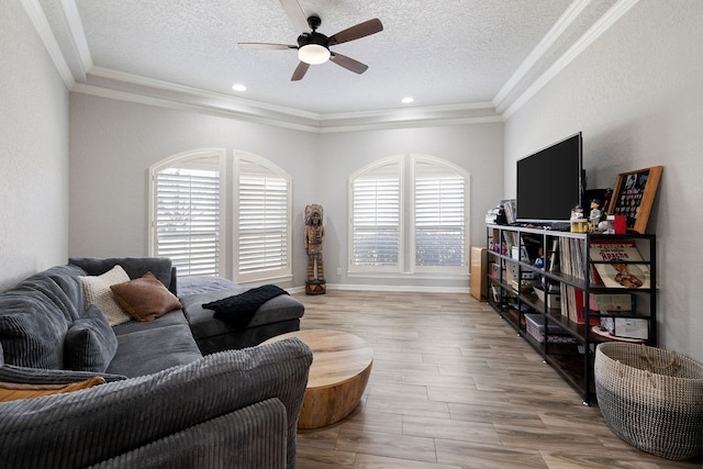 living area featuring a healthy amount of sunlight, a textured ceiling, crown molding, and a ceiling fan