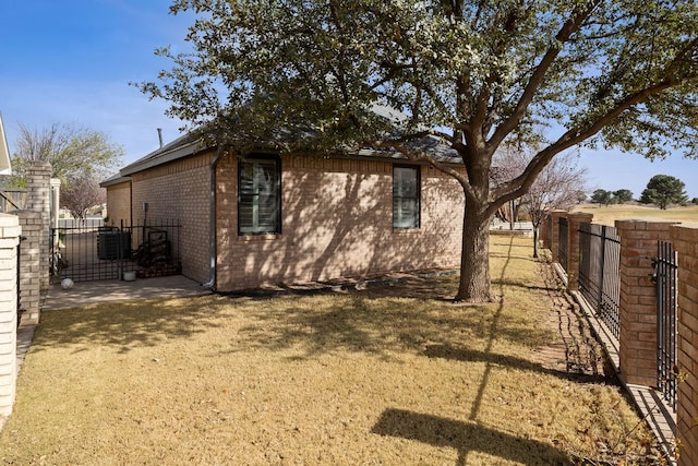 view of side of home featuring fence, brick siding, and central AC